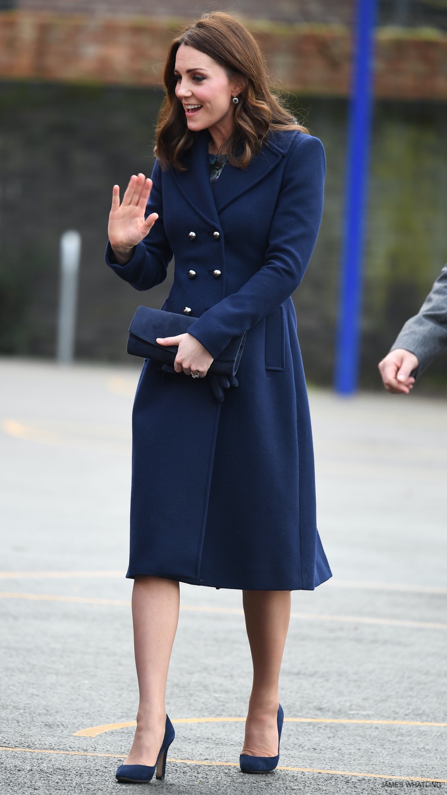 Kate Middleton wearing the Hobbs Gianna Coat in navy blue, carrying her Stuart Weitzman clutch bag and matching heels.