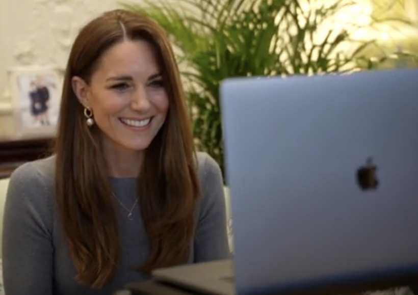 The Princess of Wales smiling, sitting at a laptop, taking part in a zoom call wearing a fine knit sweater in grey, by Alexander McQueen