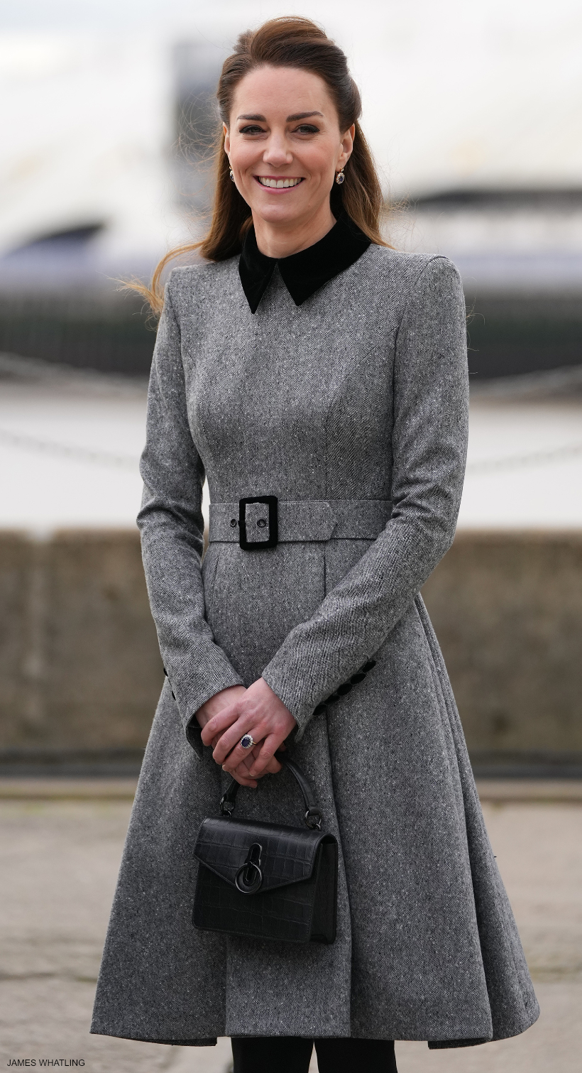 The Duchess of Cambridge (Kate Middleton) wearing a smart grey coat dress. She carries a black croc-print bag with matching black hardware.