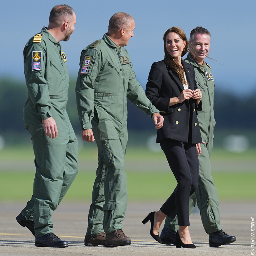 Kate Middleton walking with officers, wearing the black twill blazer with gold buttons from Holland Cooper