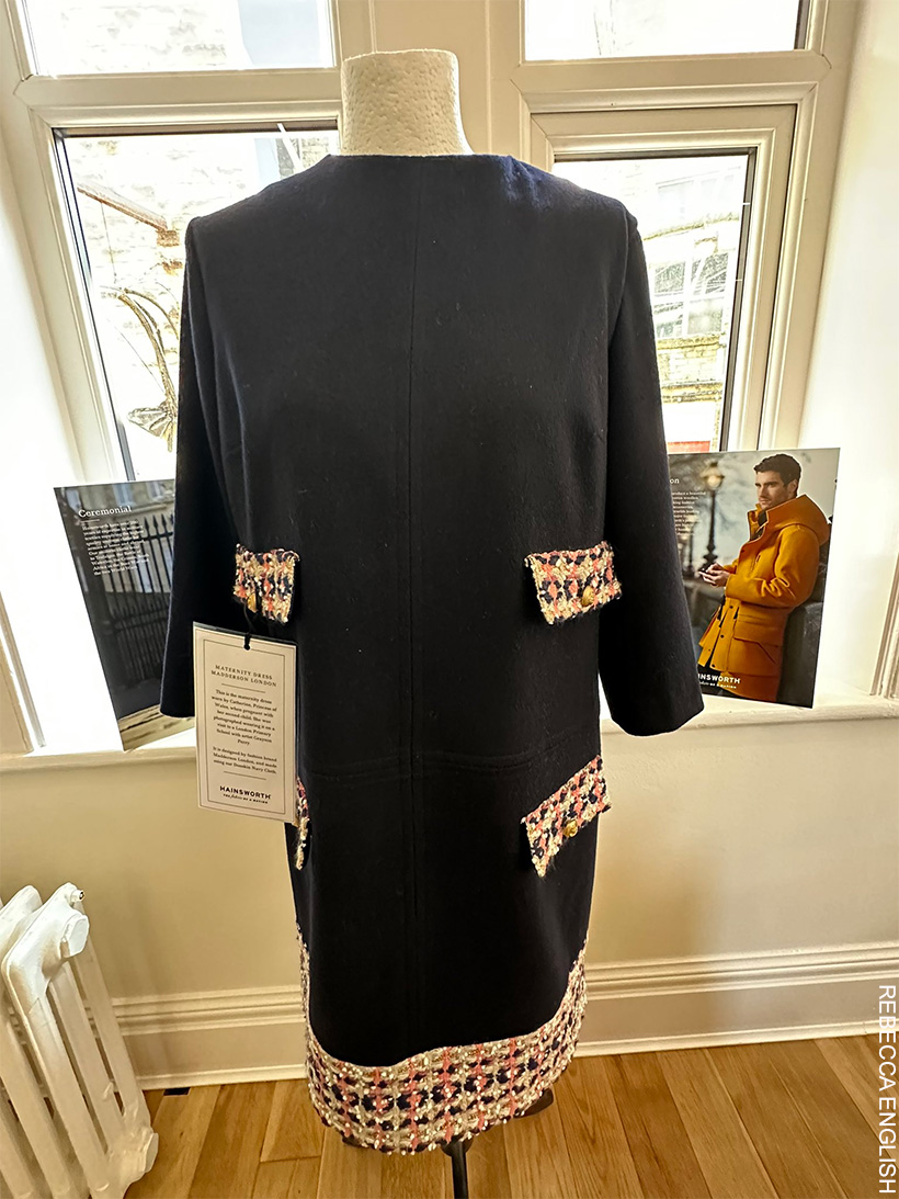 A navy blue Maternity dress with tweed pocket flaps and tweed hem, on a mannequin.