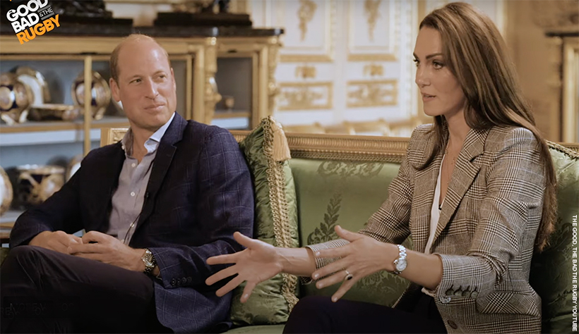 William and Kate talking to the podcast hosts. Kate, dressed in her check blazer, is talking with her hands open. William is looking at her, smiling.