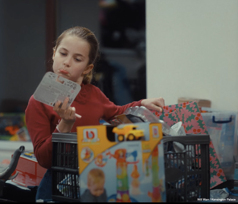 Charlotte looks at a toy and ponders whether or not to put it in her bag, pursing her lips as she thinks