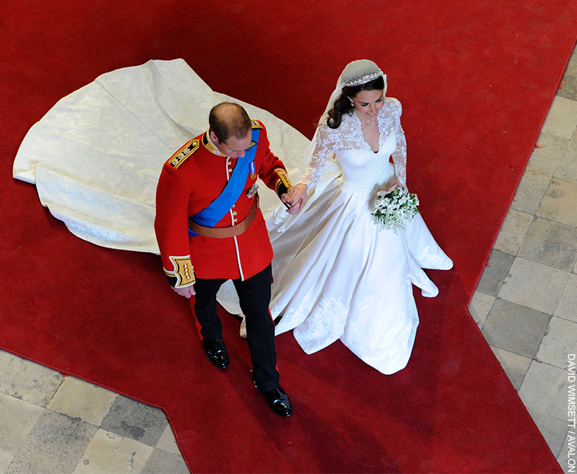 William and Kate walk hand in hand through Westminster Abbey, as husband and wife. Both wearing wedding attire, Kate's dress train following behind.
