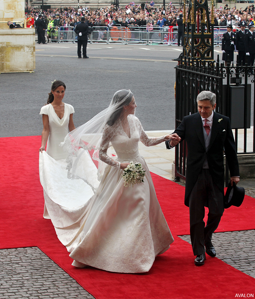 Clad in her white wedding dress, Kate Middleton takes her father's hand as she steps into Westminster Abbey. Sister Pippa holds the bride's train.