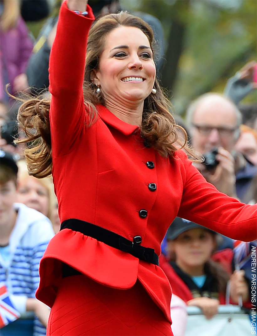 Kate Middleton wearing a vibrant red Luisa Spagnoli suit with a black belt and pearl earrings during her visit to Christchurch. she is attempting to catch a cricket ball.