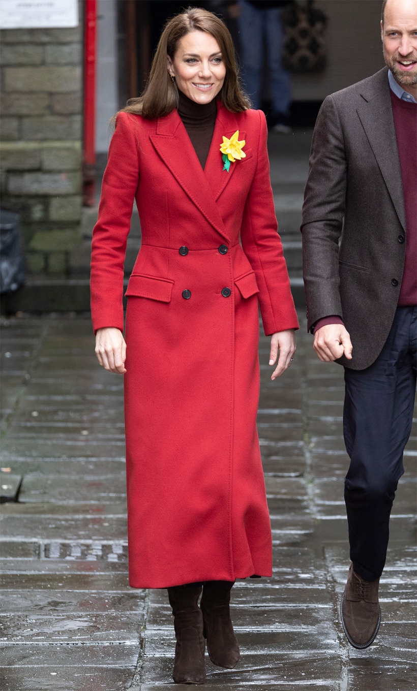 The Princess of Wales in a vibrant red coat and brown boots, walking through a street in Pontypridd Wales, with a daffodil pinned on her lapel.