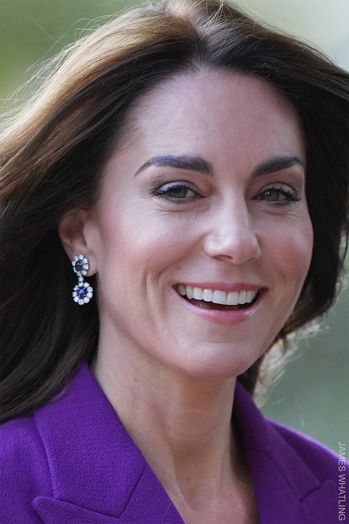 Close up of the Princess's face smiling, showing her blue sapphire earrings, and lapels from her bold purple suit