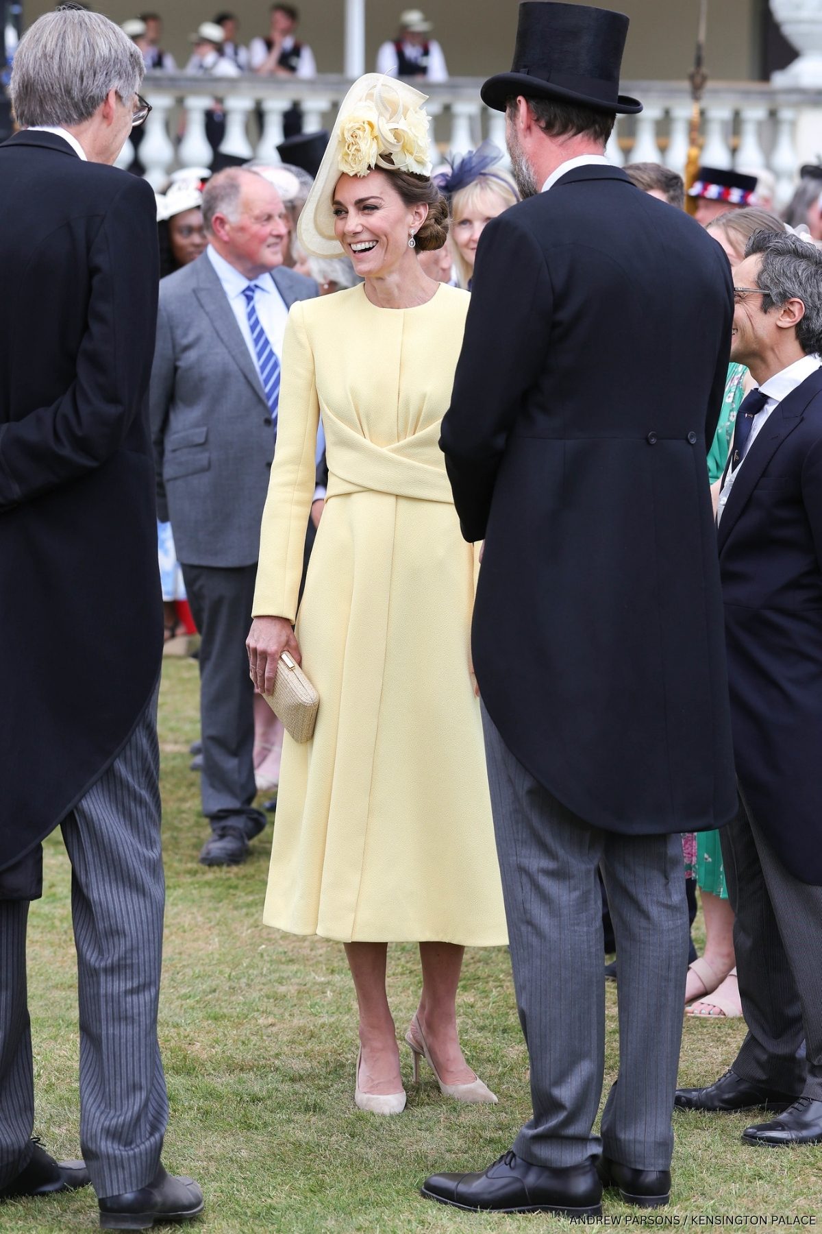Kate Middleton wearing yellow at a Buckingham Palace Garden Party. She's paired her ensemble with the neutral coloured suede slingback heels.