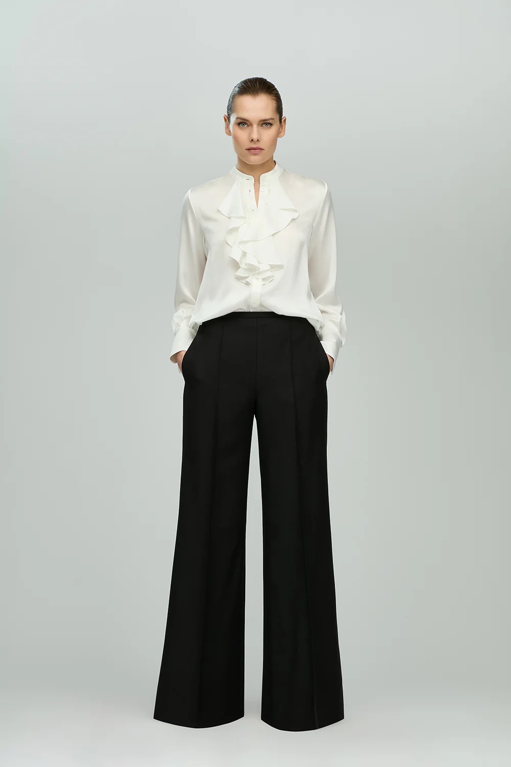 Model wearing the ruffled silk blouse with black wide leg trouers