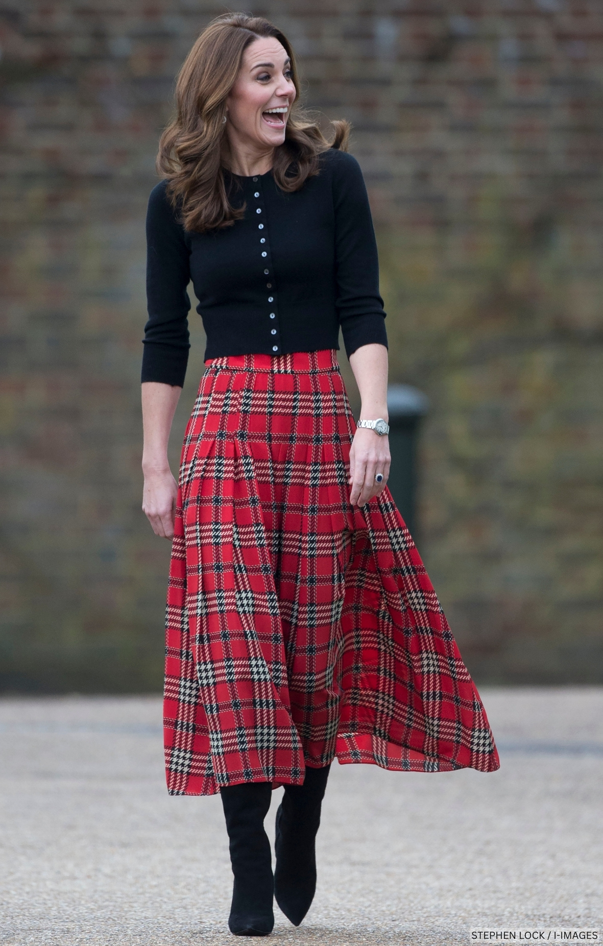 Kate Middleton wearing a red tartan skirt with a black cardigan