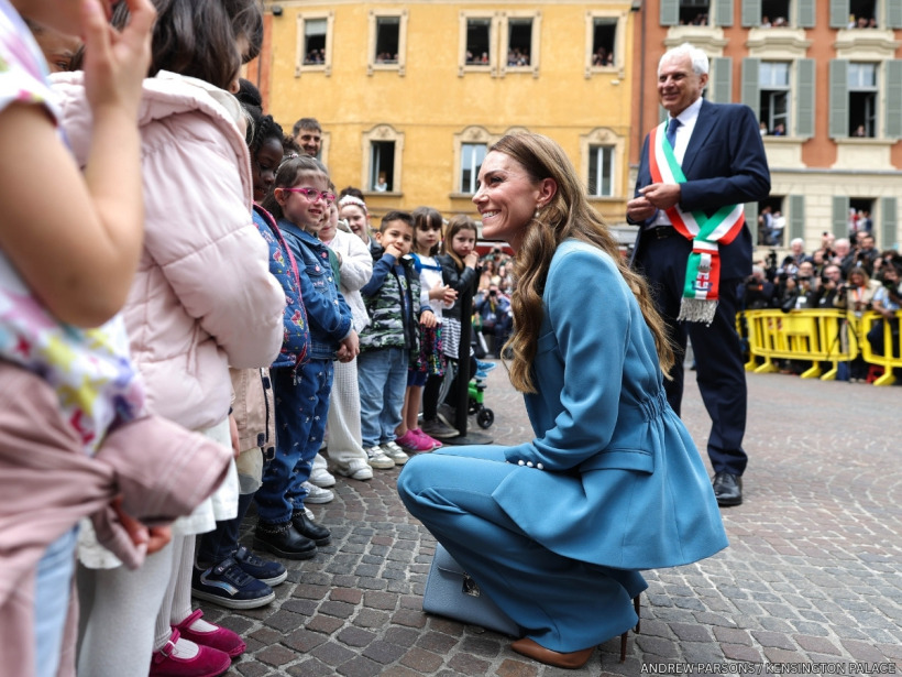 Kate Middleton crouching down to chat in Italian with pre-school children in the main square in Reggio Emilia