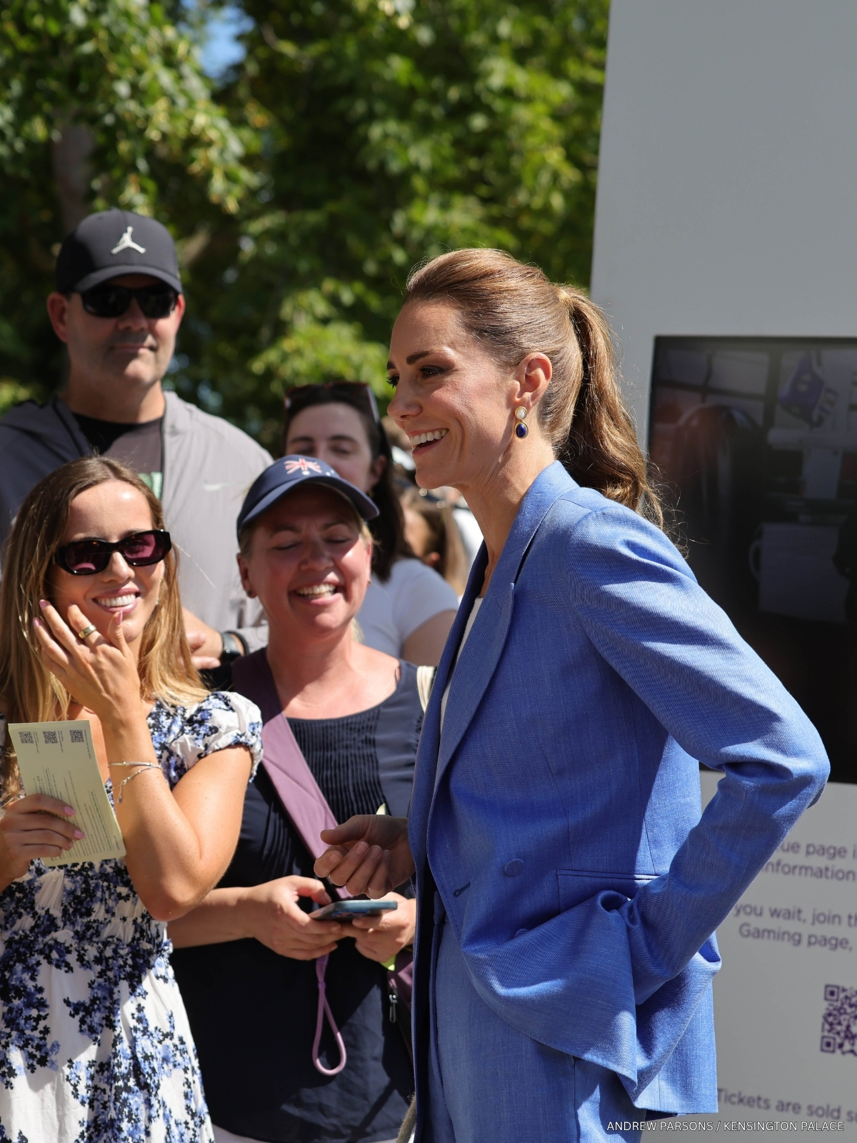Kate Middleton in a cobalt-blue Gabriela Hearst suit chatting with people in The Queue at Wimbledon